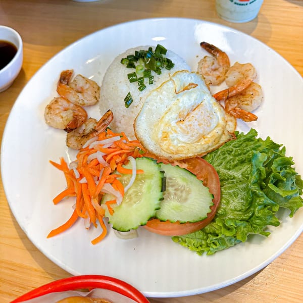 Vietnamese grilled shrimp and fried egg over rice with pickled carrots, cucumbers, and lettuce.