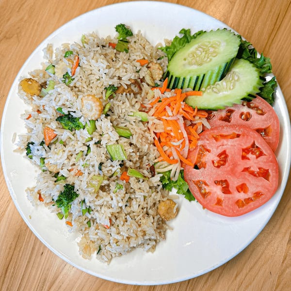 Vietvana's fried rice with vegetables, sliced cucumbers, shredded carrots, and tomatoes on a white plate.